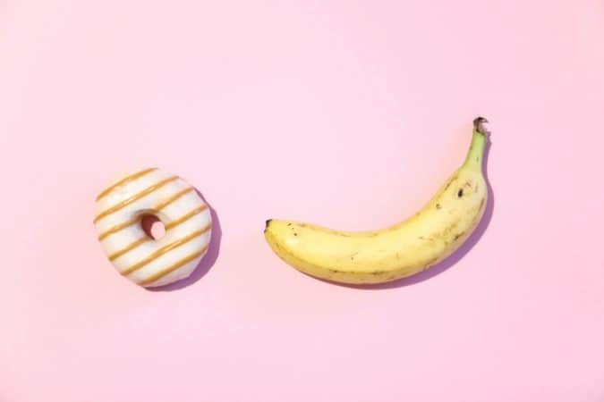 O objetivo da Omens é dar dicas sobre como usar um anel peniano . A imagem mostra uma banana e um donut em um fundo rosa.