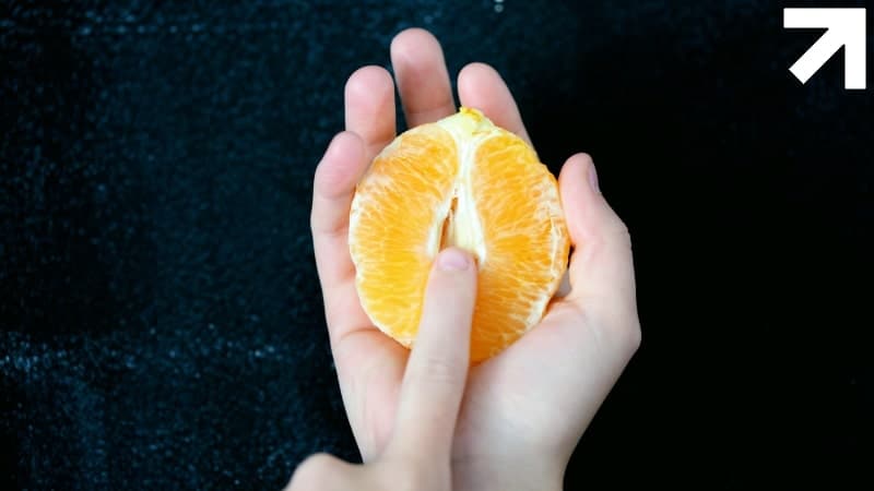 dedo penetrando uma tangerina simbolizando uma masturbação