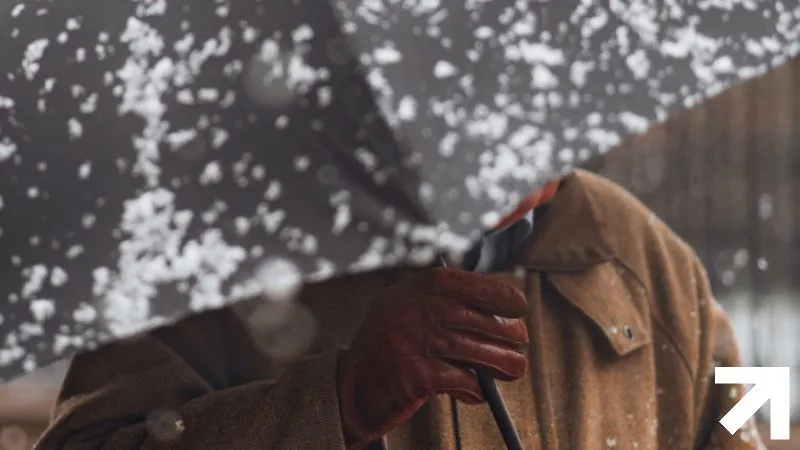 homem com guarda-chuva em meio a neve caindo, o que lembra a queda da caspa