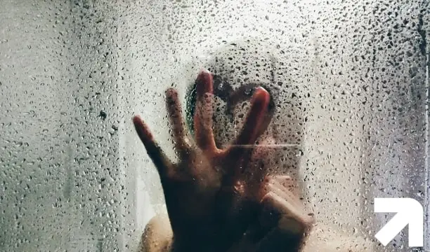 pessoa fazendo um coração no box embaçado do chuveiro