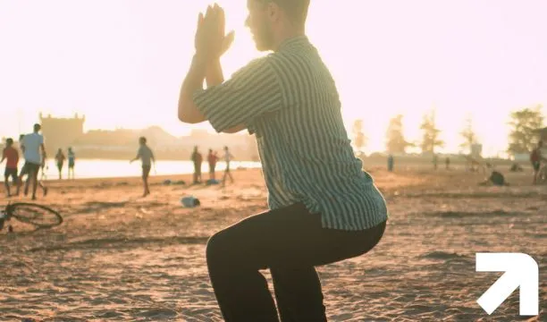 homem na praia praticando um agachamento